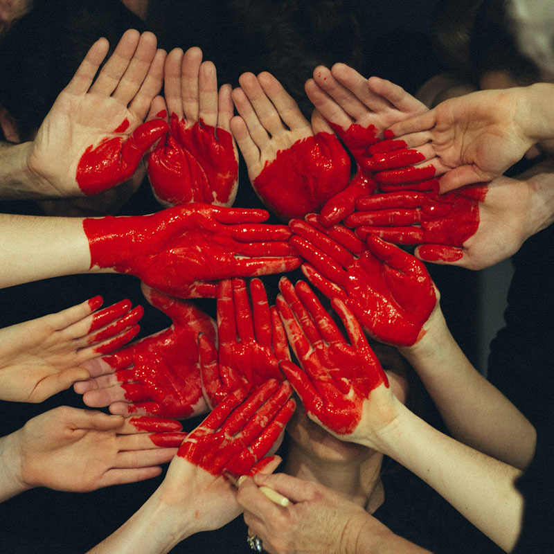 manos entrelazadas con un corazón pintado en color rojo